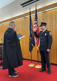 The Honorable Kyle Halesey at left administers the oath the Firefighter Joseph Scudder. 